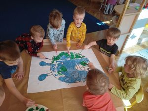 Dzieci najmłodsze malują farbami planetę Ziemię.