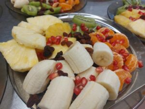 owocowo-warzywne talerze: plastry pomarańczy, ananas krojony na cząstki, banan krojony na cząstki, połówki kiwi, pestki granata.