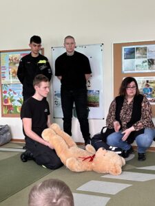 Uczniowie Zespołu Szkół przy Teatralnej w Pile, prezentujący postępowanie wobec osoby osłabionej z wykorzystaniem pluszowego misia.