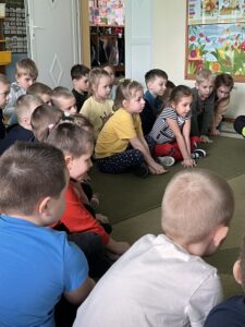Dzieci ćwiczące ucisk klatki piersiowej na dywanie (RKO).